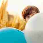 kid playing behind balloons