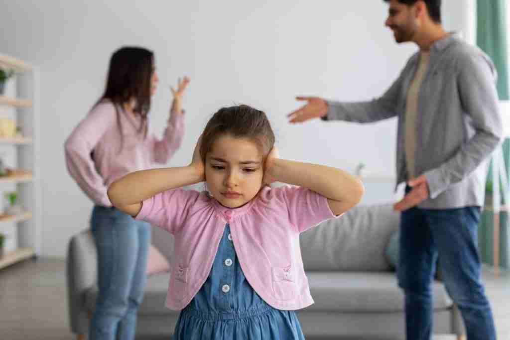 child covering her ears while parents are fighting