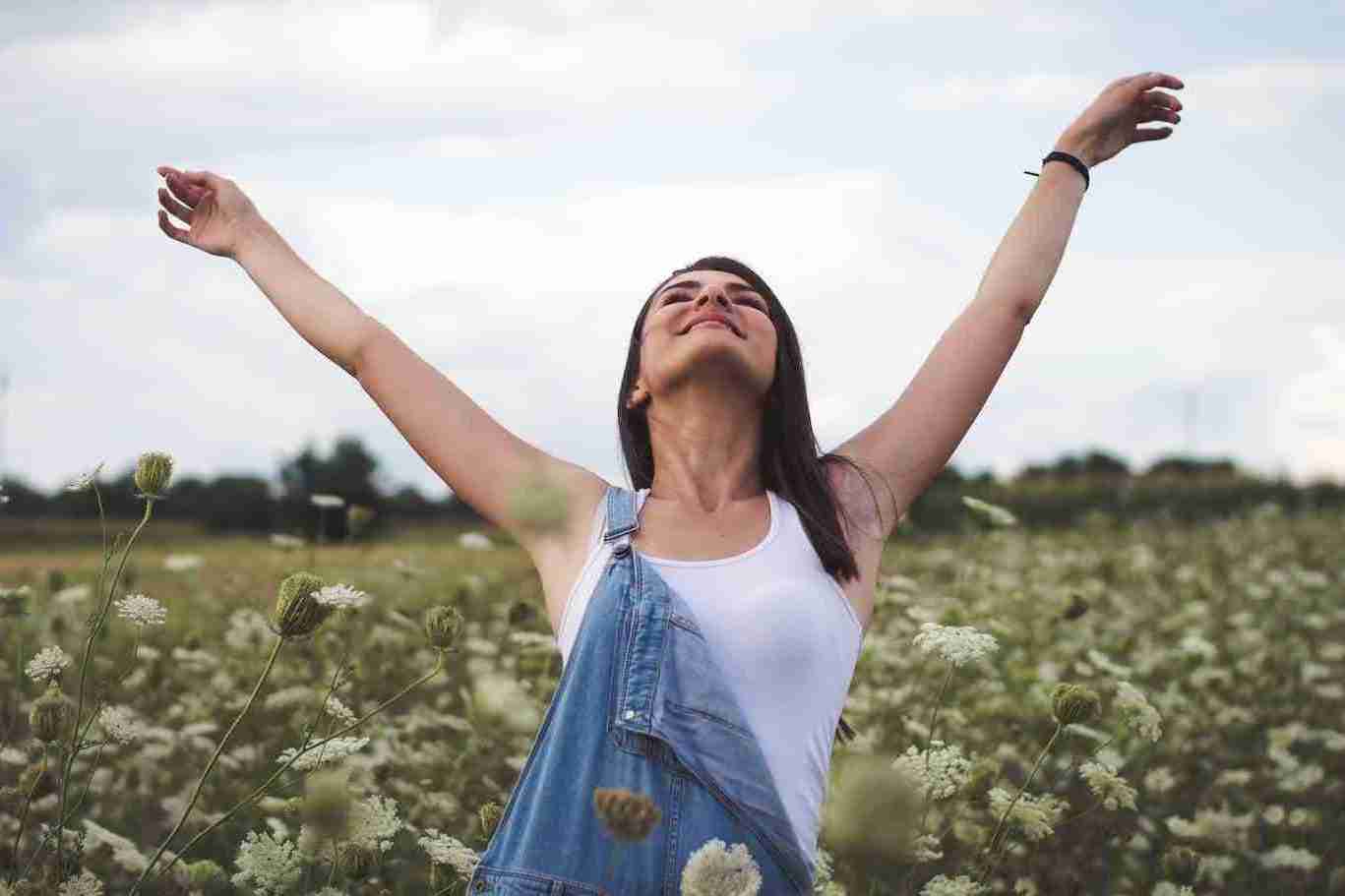 woman with open arms in a field of flowers