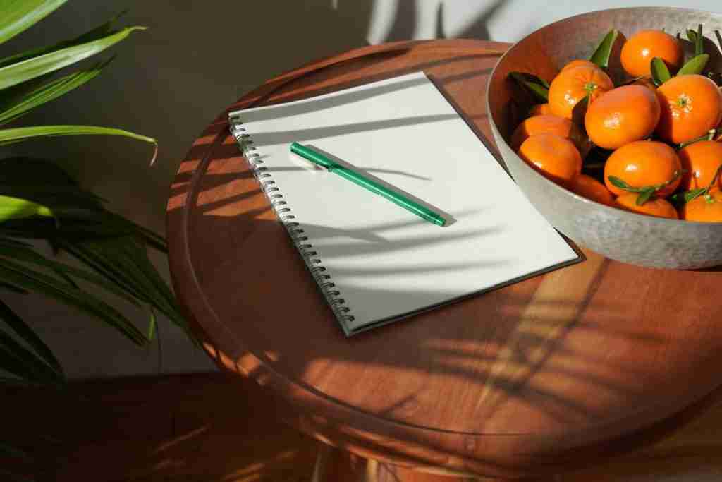 notebook beside a bowl of oranges