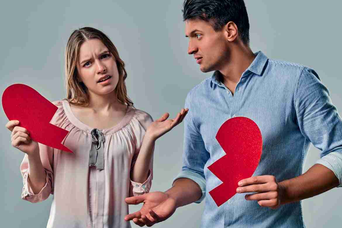 Couple arguing while holding broken hearts